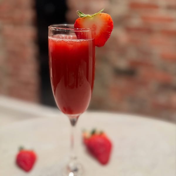 A White Maple Café strawberry mimosa in a champagne flute, garnished with a strawberry slice.