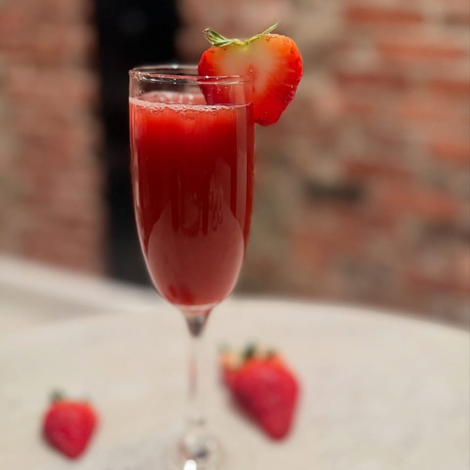 A White Maple Café strawberry mimosa in a champagne flute, garnished with a strawberry slice.