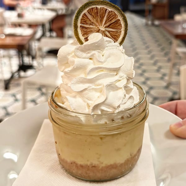 Key lime pie in a jar, topped with whipped cream and a dried lime slice.