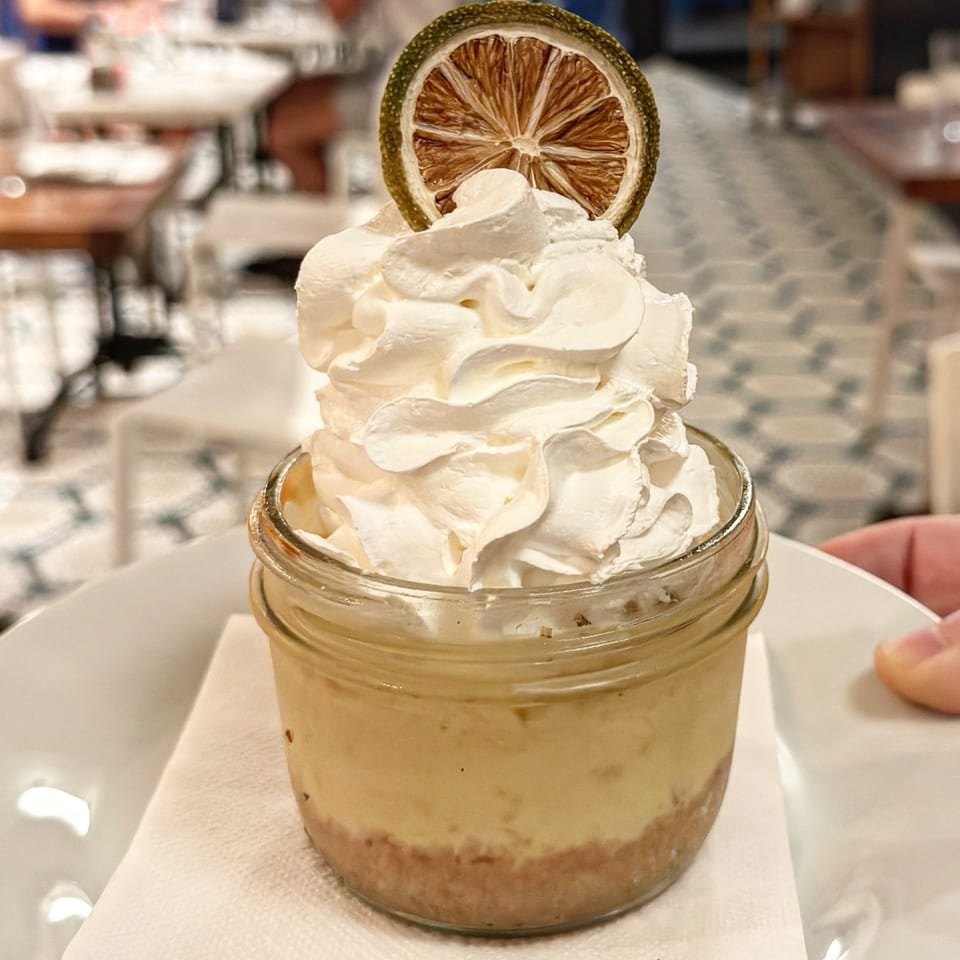 Key lime pie in a jar, topped with whipped cream and a dried lime slice.