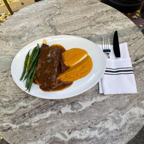 Braised short rib with green beans and sweet potato puree on a white plate at White Maple Café.